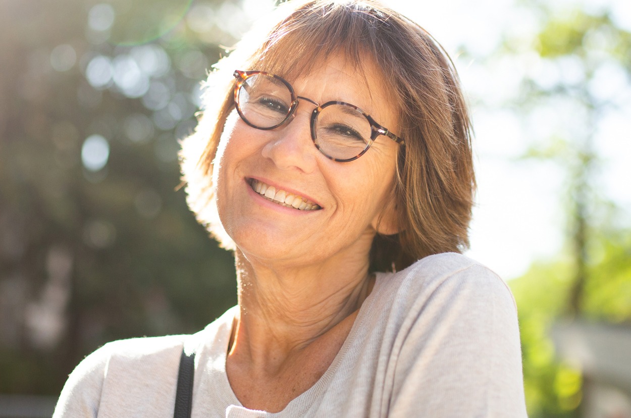 Close up older woman with eyeglasses smiling outside