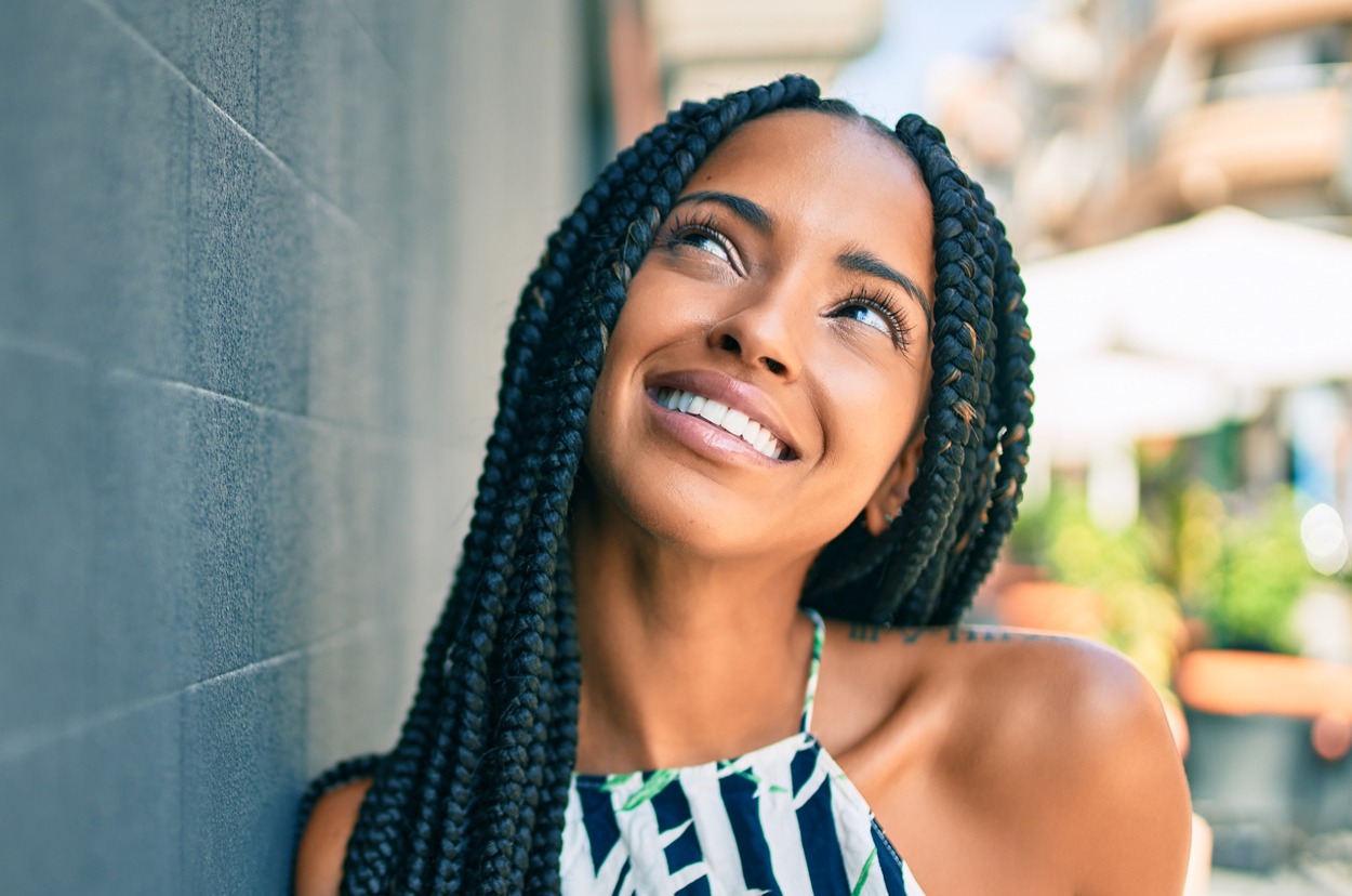 Young african american woman smiling happy leaning on the wall at the city.