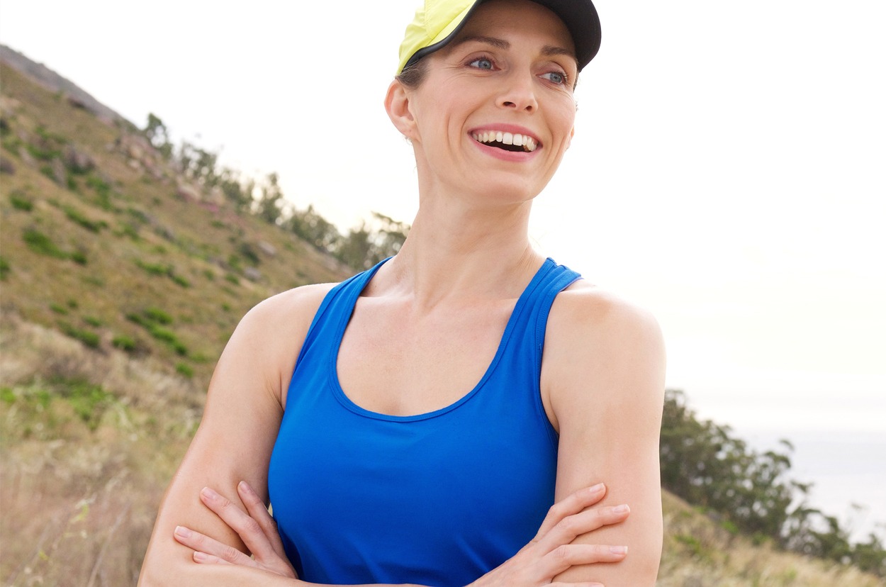 Laughing athletic woman with arms crossed outside