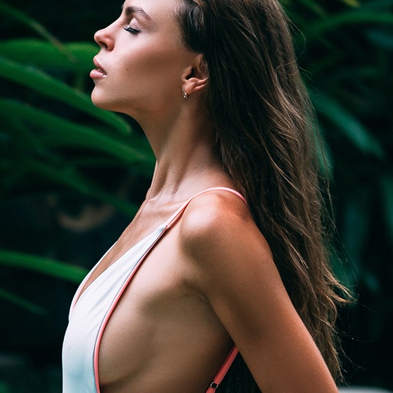 model looking off to the left wearing a white top and earrings