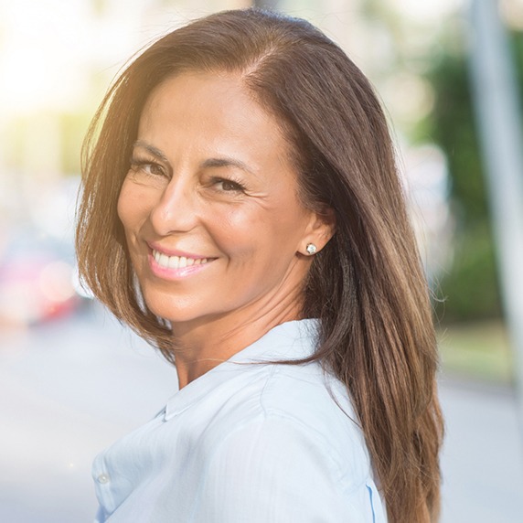 older female model smiling and looking over her shoulder wearing a blue button shirt