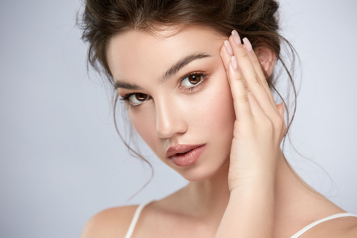 Woman with flawless skin, touching face.